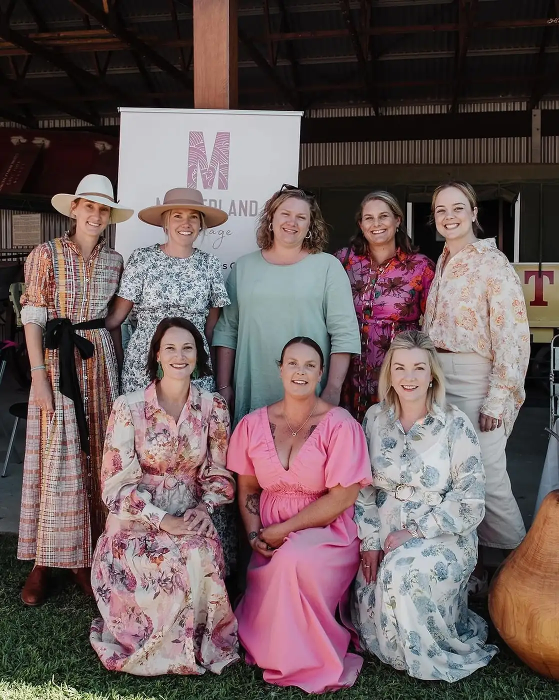 Eight Motherland Village mums together in front of a Motherland banner