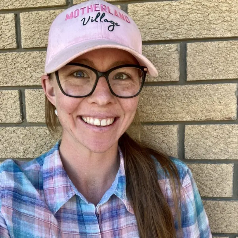 Smiling Queensland mum wearing a pink Motherland Village cap